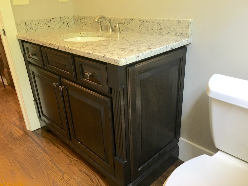 Photo of a mid-sized transitional powder room in Atlanta with raised-panel cabinets, dark wood cabinets, medium hardwood floors and an undermount sink.