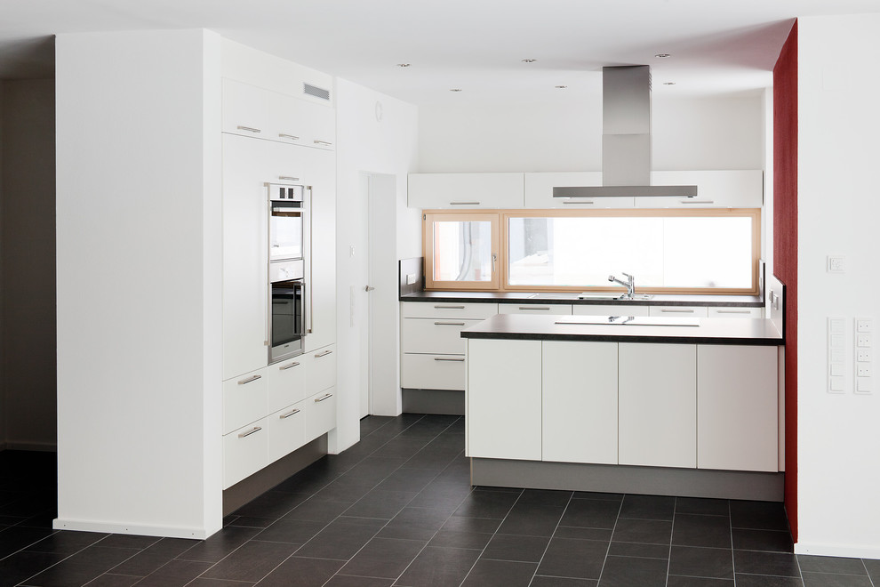 Design ideas for a mid-sized contemporary open plan kitchen in Stuttgart with flat-panel cabinets, white cabinets, a peninsula, a drop-in sink, glass sheet splashback and stainless steel appliances.