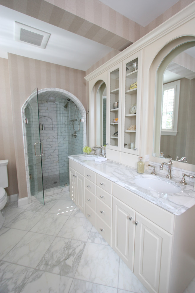 Design ideas for a large traditional master bathroom in Charlotte with beige cabinets, an alcove shower, a two-piece toilet, beige walls, porcelain floors, an undermount sink, raised-panel cabinets, gray tile, subway tile, marble benchtops and a claw-foot tub.
