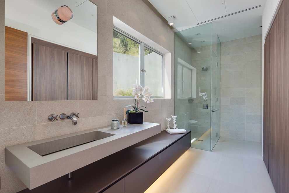 Large modern 3/4 bathroom in Los Angeles with a hinged shower door, flat-panel cabinets, dark wood cabinets, a corner shower, gray tile, stone tile, grey walls, vinyl floors, a trough sink and solid surface benchtops.
