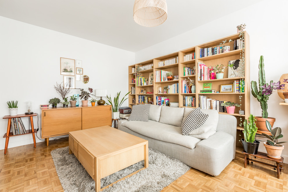 Design ideas for a scandinavian open concept living room in Paris with light hardwood floors, a library, white walls and brown floor.