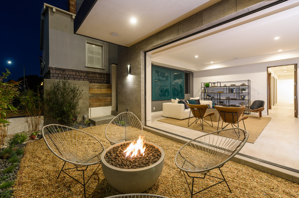 Trendy front yard gravel patio photo in Los Angeles with a fire pit and a roof extension
