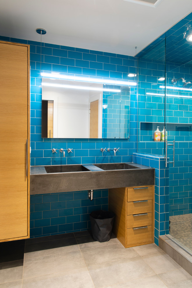 Inspiration for a mid-sized contemporary kids bathroom in Omaha with flat-panel cabinets, blue tile, blue walls, porcelain floors, an integrated sink, concrete benchtops, a hinged shower door, grey benchtops, medium wood cabinets, an alcove shower, subway tile and beige floor.