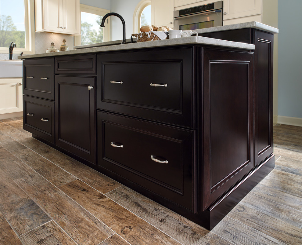 Transitional medium tone wood floor and brown floor enclosed kitchen photo with recessed-panel cabinets, dark wood cabinets, stainless steel appliances and an island