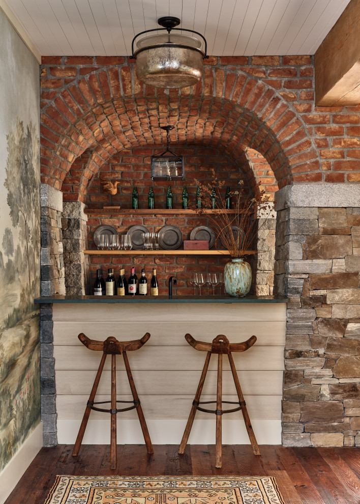 Idées déco pour un bar de salon parallèle campagne avec des tabourets, une crédence rouge, une crédence en brique, parquet foncé et un sol marron.