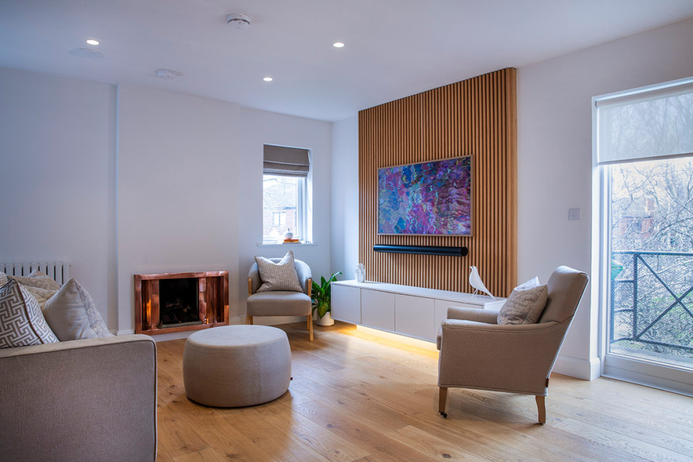 Kleines, Offenes Modernes Wohnzimmer mit weißer Wandfarbe, hellem Holzboden, Kaminumrandung aus Metall und Multimediawand in Dublin
