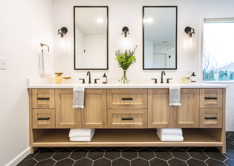 Design ideas for a mid-sized country master bathroom in Seattle with shaker cabinets, light wood cabinets, a freestanding tub, a corner shower, a one-piece toilet, white tile, subway tile, white walls, porcelain floors, an undermount sink, black floor, a hinged shower door, white benchtops and engineered quartz benchtops.