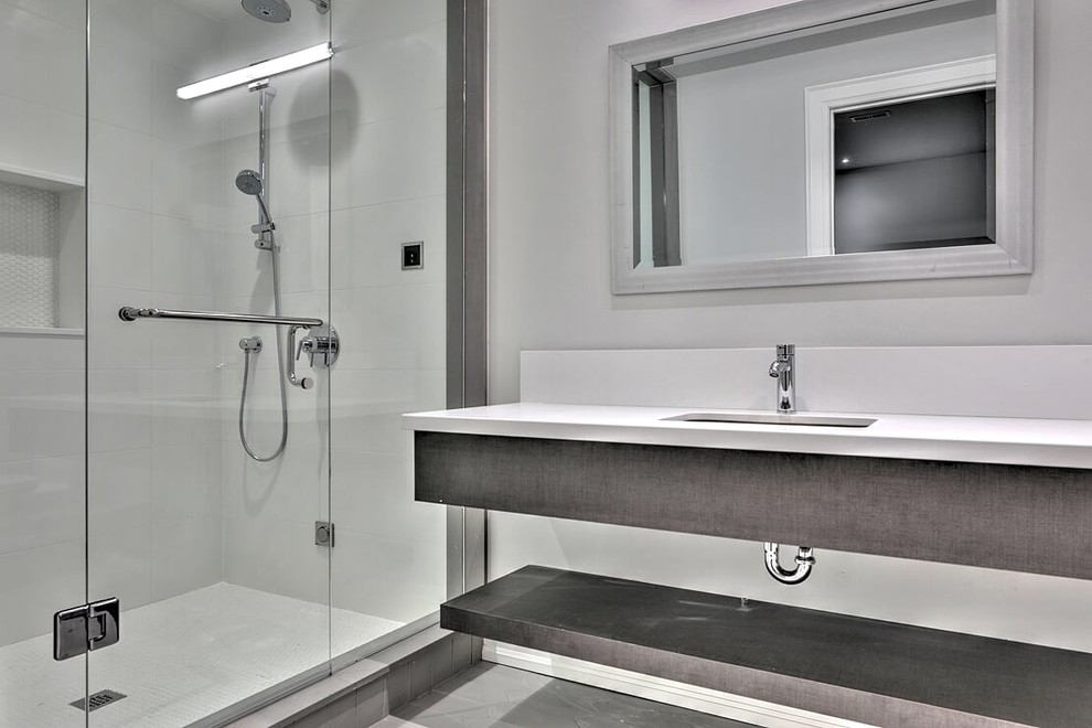 Mid-sized scandinavian 3/4 bathroom in Toronto with open cabinets, grey cabinets, an alcove shower, a two-piece toilet, white tile, ceramic tile, grey walls, cement tiles, a wall-mount sink, solid surface benchtops, grey floor, a hinged shower door and white benchtops.