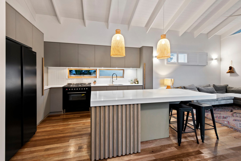 Inspiration for a small contemporary l-shaped eat-in kitchen in Brisbane with an undermount sink, grey cabinets, quartz benchtops, grey splashback, window splashback, black appliances, with island, white benchtop, flat-panel cabinets, medium hardwood floors, brown floor and exposed beam.