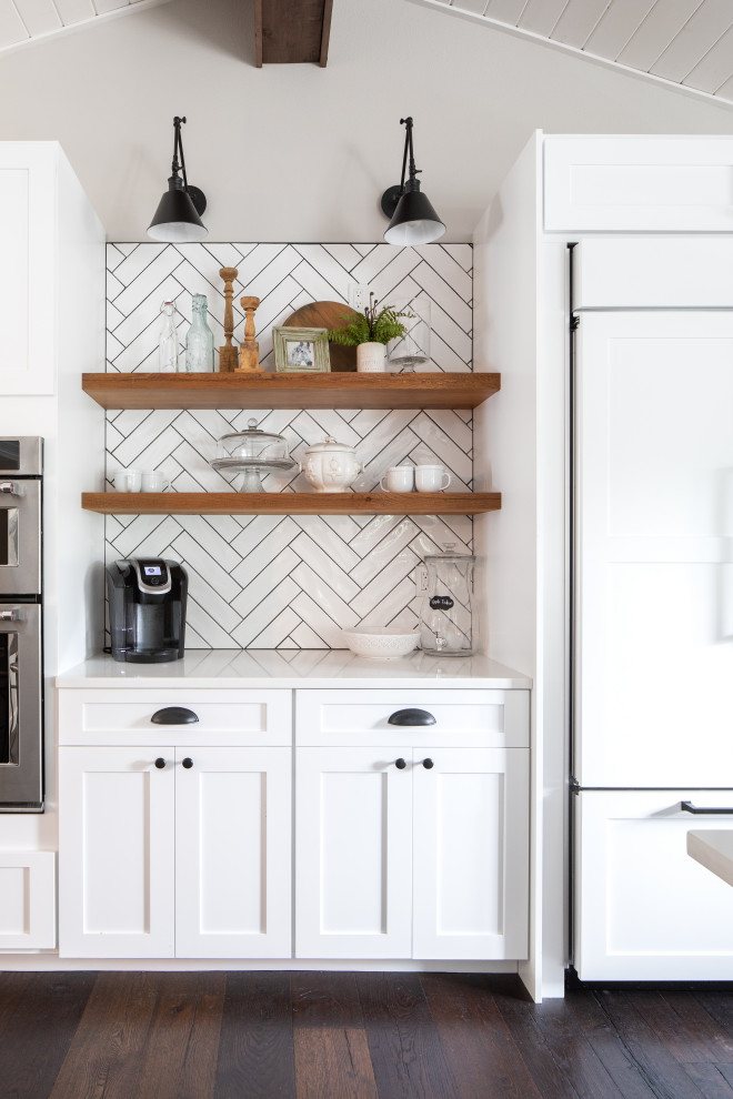 This is an example of a mid-sized country single-wall kitchen in Seattle with shaker cabinets, white cabinets, white splashback, ceramic splashback, medium hardwood floors, brown floor and white benchtop.