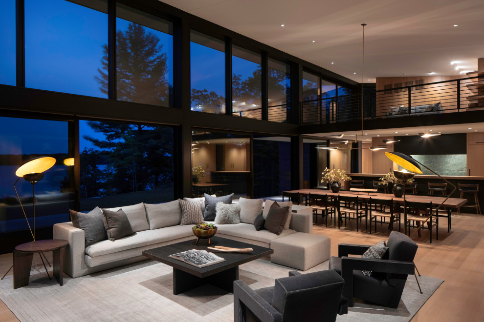 Large contemporary open plan living room in Other with black walls, light hardwood flooring, a standard fireplace, a stone fireplace surround, a concealed tv, brown floors, a vaulted ceiling and panelled walls.