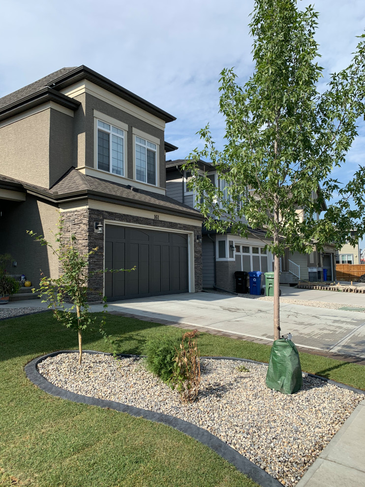 This is an example of a small traditional front yard full sun xeriscape for summer in Calgary with with privacy feature, concrete pavers and a wood fence.