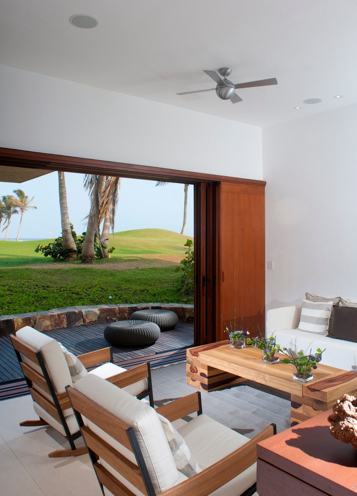 This is an example of a tropical family room in Other with white walls.