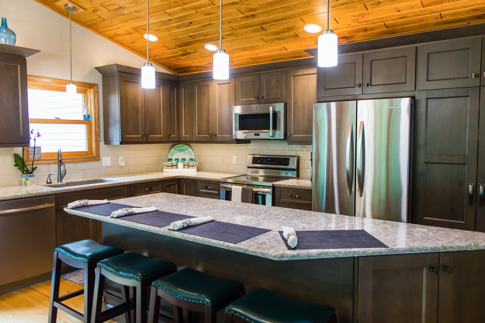 Inspiration for a transitional l-shaped brown floor eat-in kitchen remodel with dark wood cabinets, quartzite countertops, beige backsplash, ceramic backsplash, stainless steel appliances, an island and beige countertops