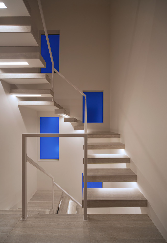 Modern u-shaped staircase in Fukuoka with open risers and metal railing.