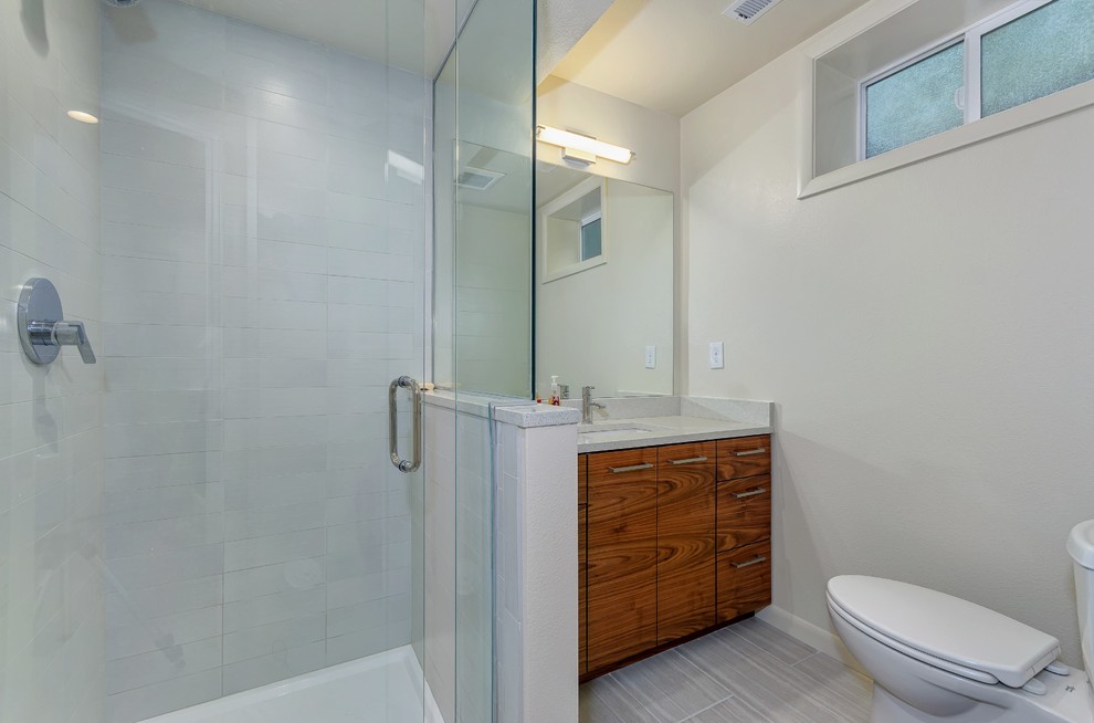 Mid-sized contemporary bathroom in Portland with an undermount sink, flat-panel cabinets, dark wood cabinets, quartzite benchtops, a corner shower, a two-piece toilet, gray tile, ceramic tile, beige walls and ceramic floors.