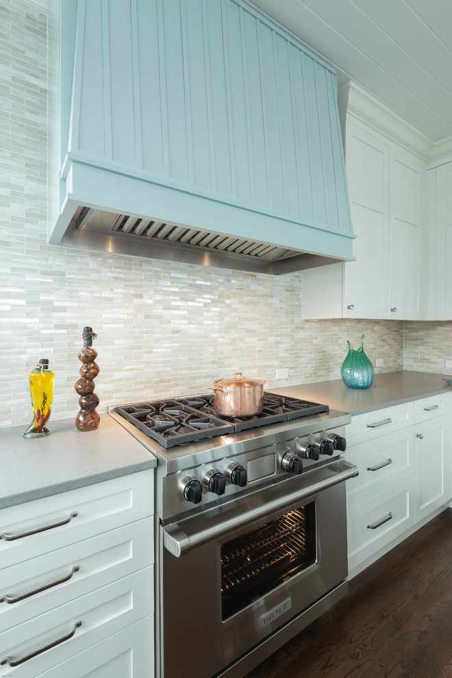 Example of a large beach style l-shaped medium tone wood floor and brown floor eat-in kitchen design in DC Metro with an undermount sink, beaded inset cabinets, white cabinets, solid surface countertops, multicolored backsplash, matchstick tile backsplash, stainless steel appliances, an island and gray countertops