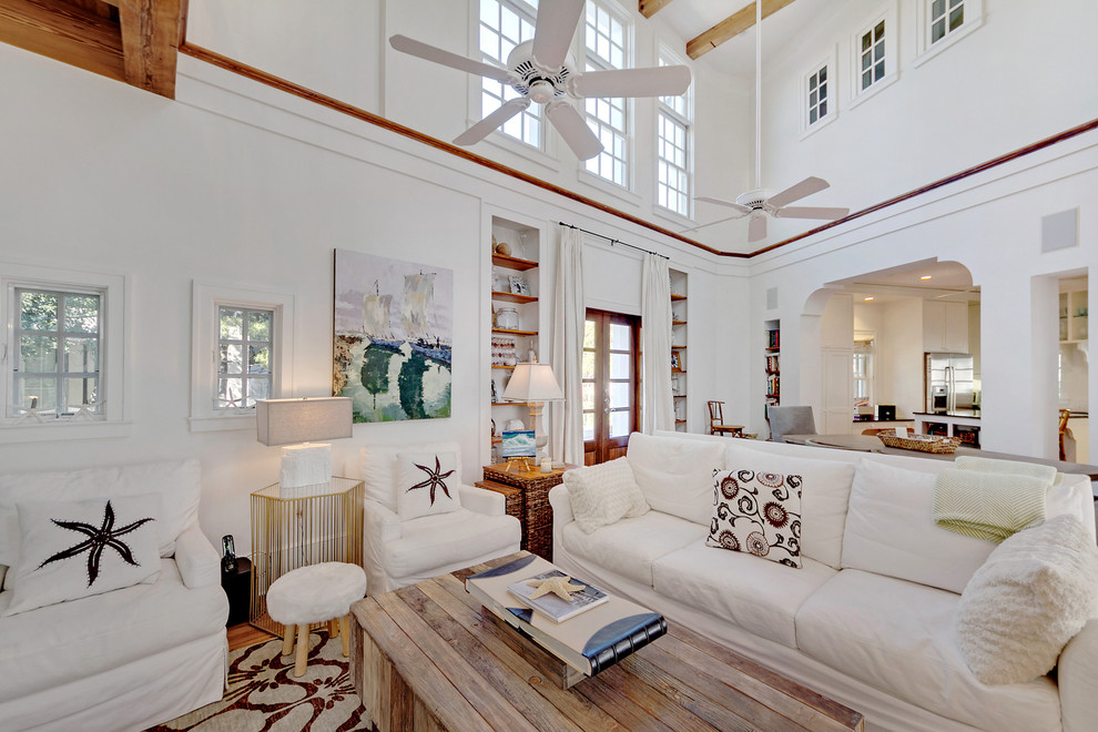 This is an example of a large beach style loft-style living room in Miami with white walls and light hardwood floors.