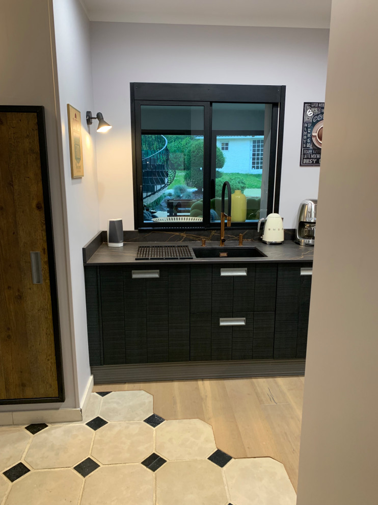 This is an example of a medium sized bohemian open plan kitchen in Nancy with an integrated sink, beaded cabinets, medium wood cabinets, granite worktops, beige splashback, ceramic splashback, integrated appliances, ceramic flooring, beige floors and black worktops.