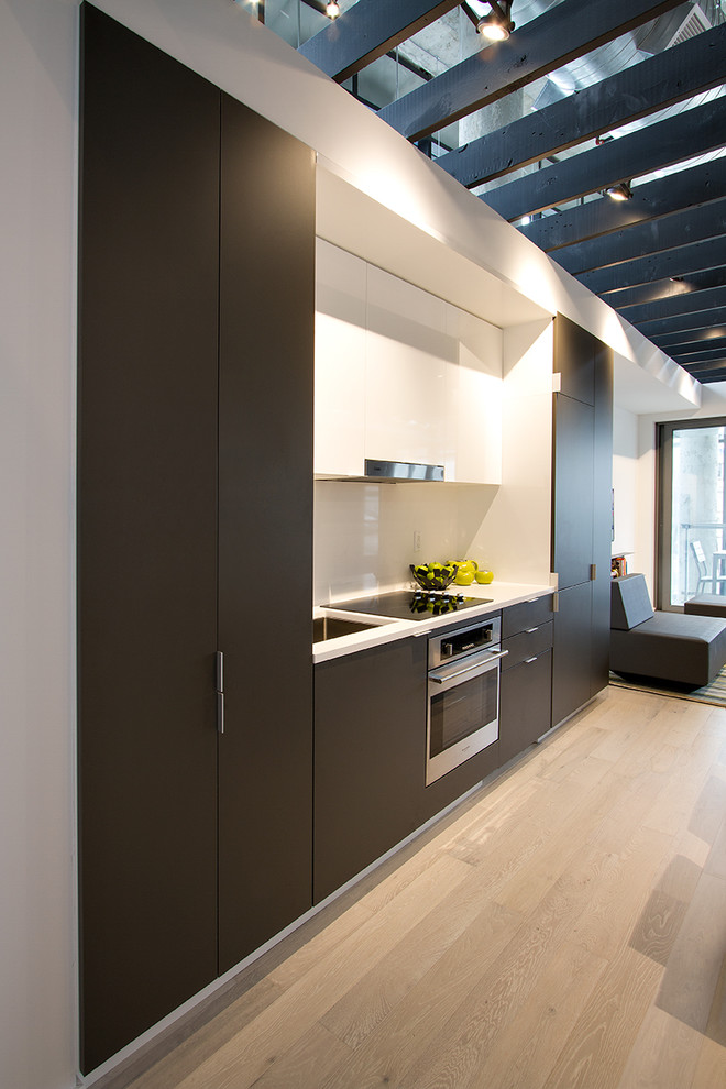 Design ideas for a small contemporary single-wall eat-in kitchen in Toronto with flat-panel cabinets, grey cabinets, white splashback, stainless steel appliances, light hardwood floors, an undermount sink and white benchtop.