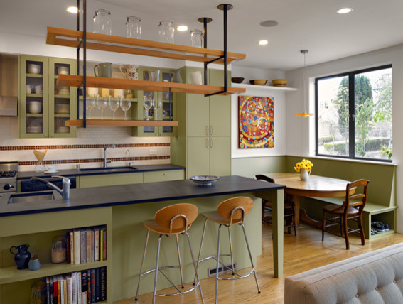 Inspiration for a mid-sized eclectic u-shaped open plan kitchen in San Francisco with an undermount sink, glass-front cabinets, green cabinets, white splashback, ceramic splashback, light hardwood floors, with island, stainless steel appliances and granite benchtops.