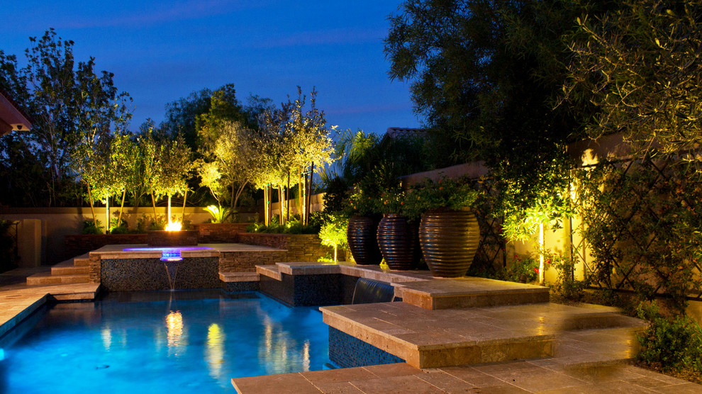 This is an example of a large mediterranean backyard custom-shaped natural pool in Las Vegas with natural stone pavers.
