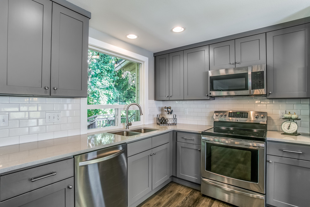 Eat-in kitchen - mid-sized transitional l-shaped dark wood floor and brown floor eat-in kitchen idea with an undermount sink, shaker cabinets, gray cabinets, quartz countertops, white backsplash, subway tile backsplash, stainless steel appliances and an island