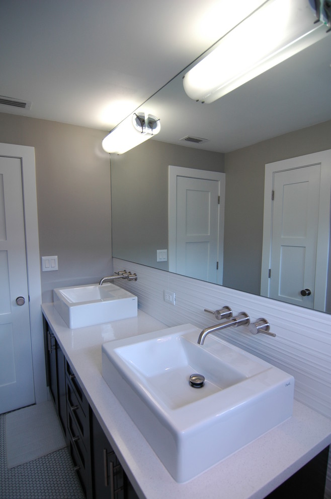 Photo of a tropical bathroom in Miami with a vessel sink, shaker cabinets, dark wood cabinets, solid surface benchtops, white tile and porcelain tile.