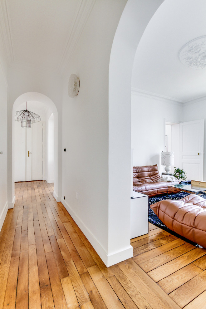 Aménagement d'un couloir rétro de taille moyenne avec un mur blanc, parquet clair et un sol beige.