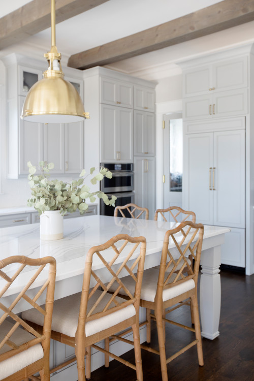 Light and airy kitchen cabinet design with white floor-to-ceiling shaker cabinets, brass pendant, quartz island, and rattan stools