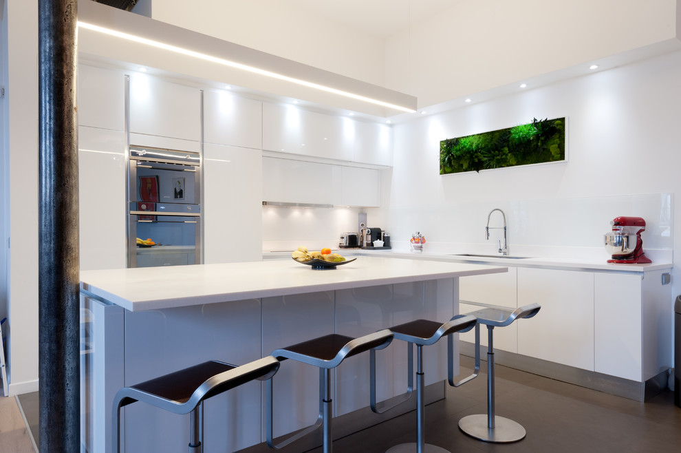 This is an example of a mid-sized modern l-shaped eat-in kitchen in Paris with an integrated sink, beaded inset cabinets, white cabinets, quartzite benchtops, white splashback, glass tile splashback, panelled appliances, terra-cotta floors and with island.