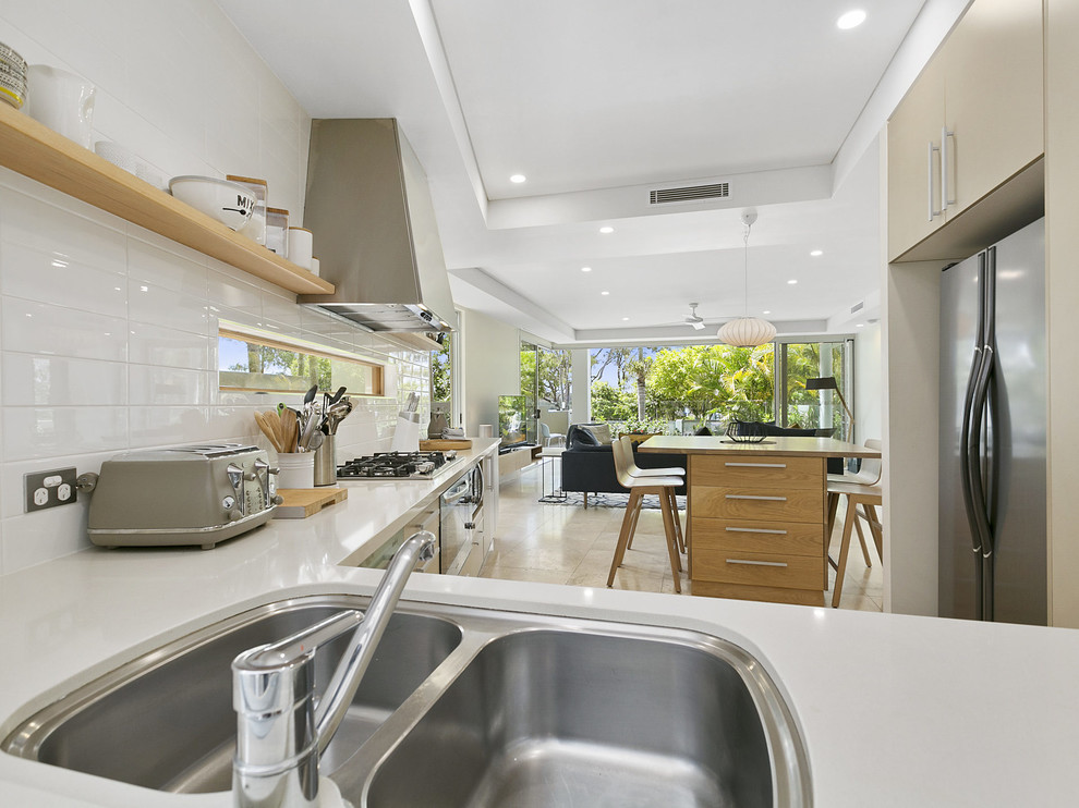 This is an example of a contemporary kitchen in Sunshine Coast with light wood cabinets, wood benchtops and subway tile splashback.