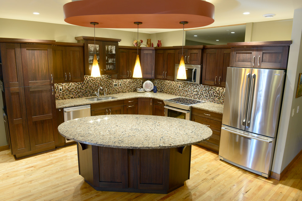 Mid-sized transitional l-shaped light wood floor open concept kitchen photo with an undermount sink, shaker cabinets, dark wood cabinets, quartzite countertops, multicolored backsplash, mosaic tile backsplash, stainless steel appliances and an island
