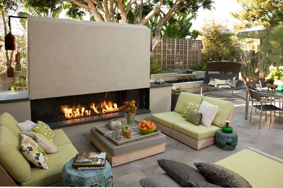 This is an example of a midcentury courtyard patio in San Diego with with fireplace and no cover.