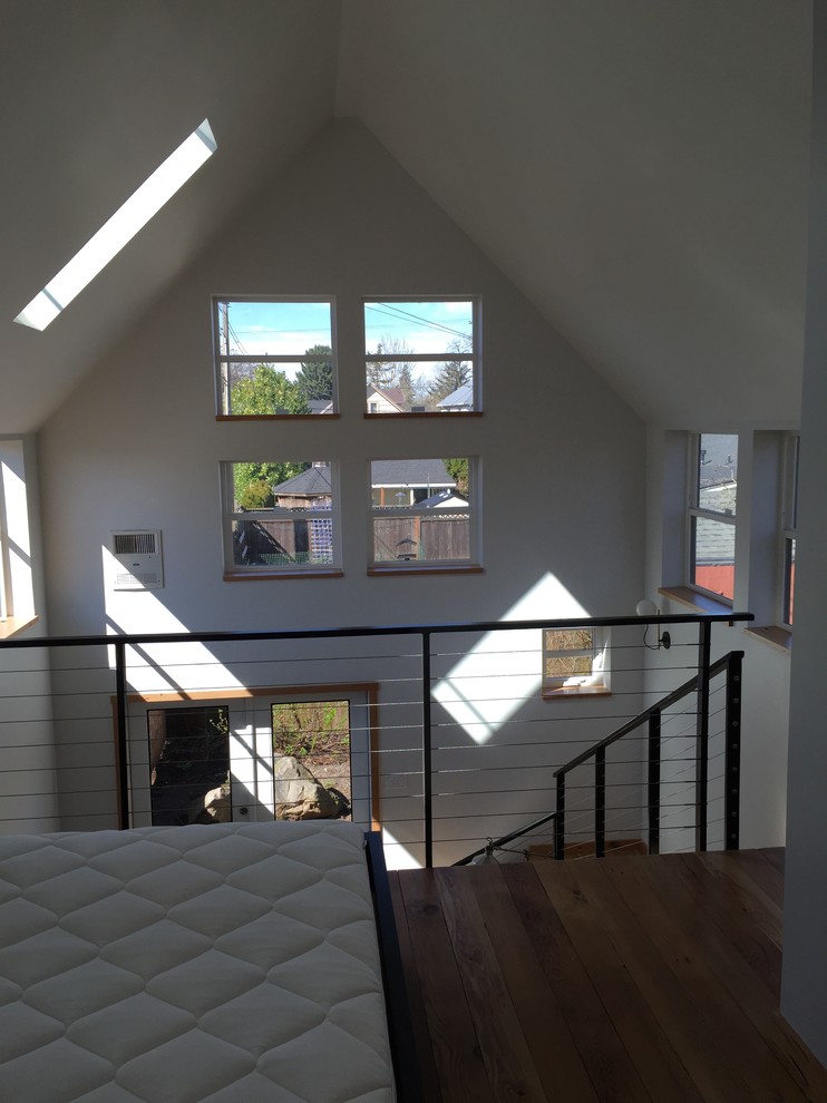 This is an example of a small modern loft-style bedroom in Portland with white walls and medium hardwood floors.