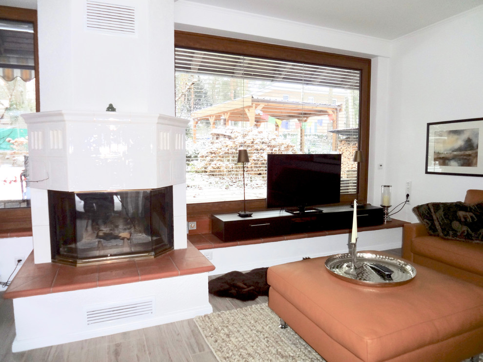 Großes, Offenes Stilmix Wohnzimmer mit weißer Wandfarbe, Kamin, freistehendem TV, Porzellan-Bodenfliesen, gefliester Kaminumrandung und beigem Boden in Berlin