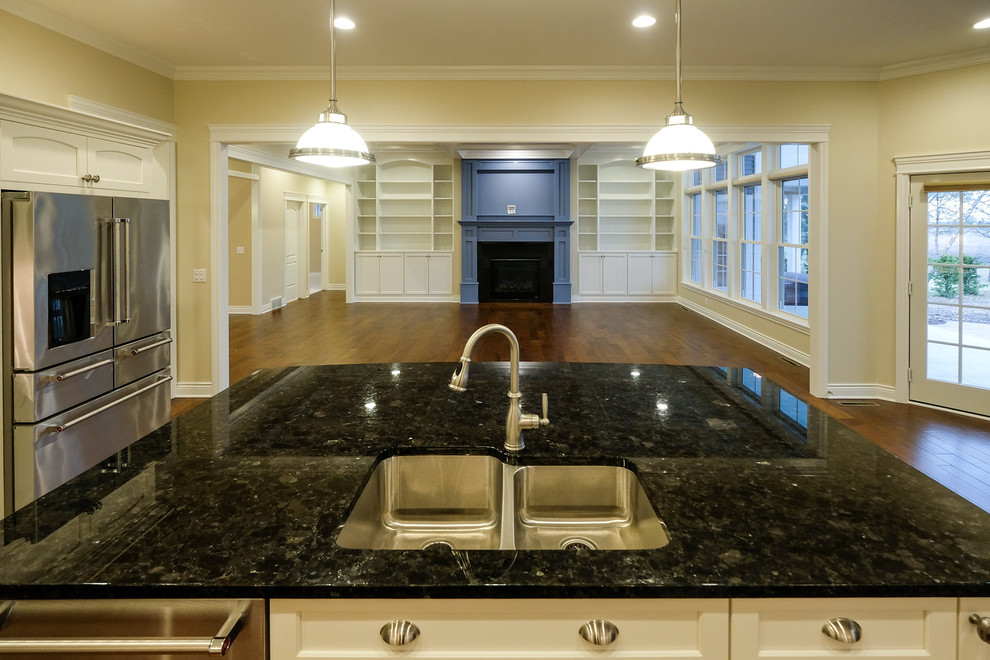 Example of a large transitional l-shaped dark wood floor and brown floor eat-in kitchen design with an undermount sink, recessed-panel cabinets, white cabinets, granite countertops, white backsplash, stainless steel appliances, an island and blue countertops