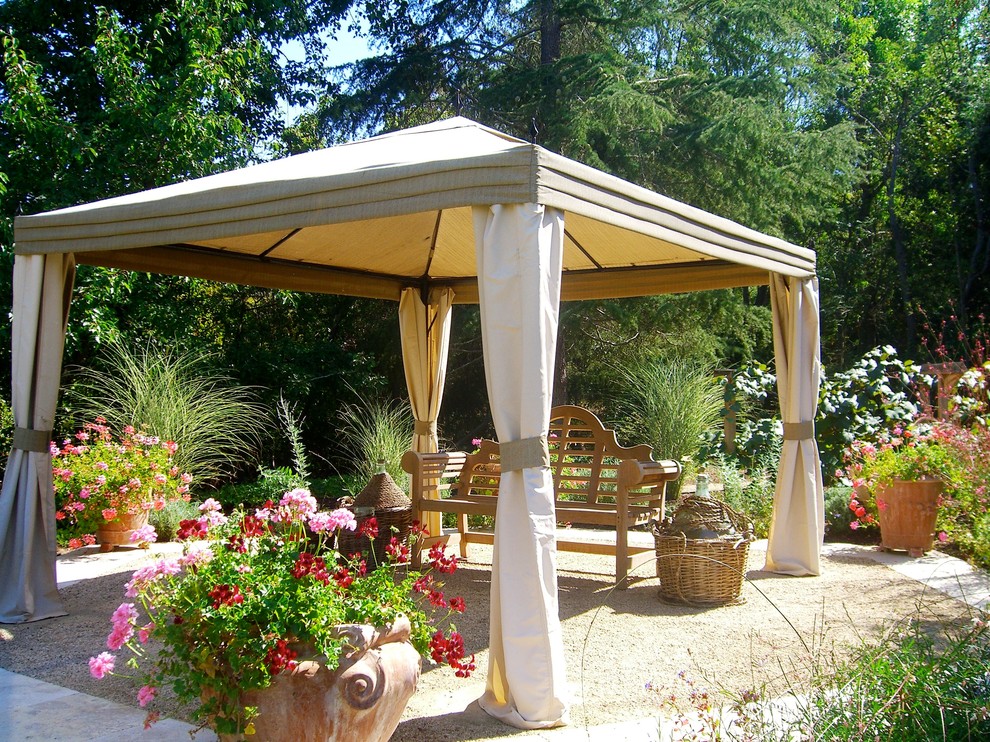 This is an example of a large mediterranean backyard patio in San Francisco with a container garden, gravel and a gazebo/cabana.