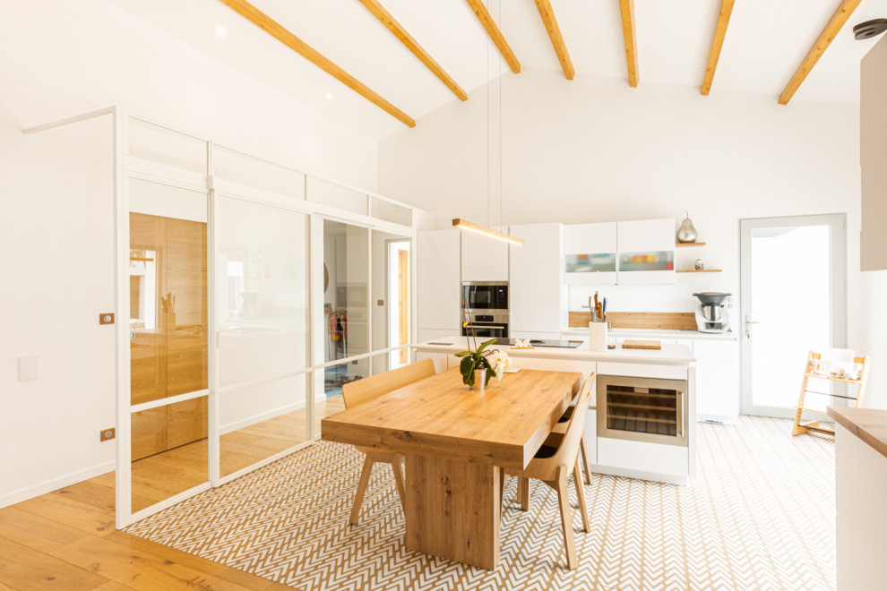 Design ideas for a large contemporary galley open plan kitchen in Other with a single-bowl sink, brown splashback, stainless steel appliances, an island, brown floors, white worktops and exposed beams.