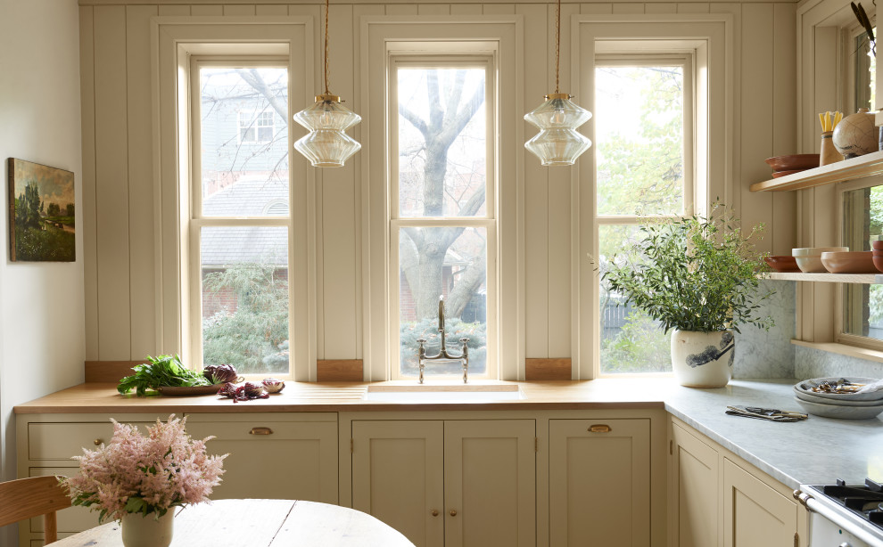 Bild på ett mellanstort vintage grå grått kök och matrum, med skåp i shakerstil, gula skåp, marmorbänkskiva, grått stänkskydd, stänkskydd i marmor, vita vitvaror, mellanmörkt trägolv och brunt golv