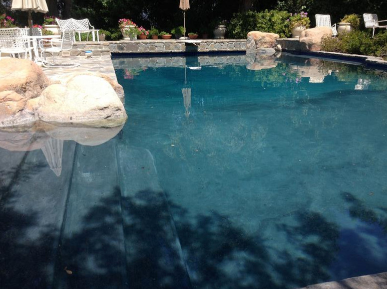 Inspiration for a rustic backyard stone and rectangular lap pool fountain remodel in Los Angeles