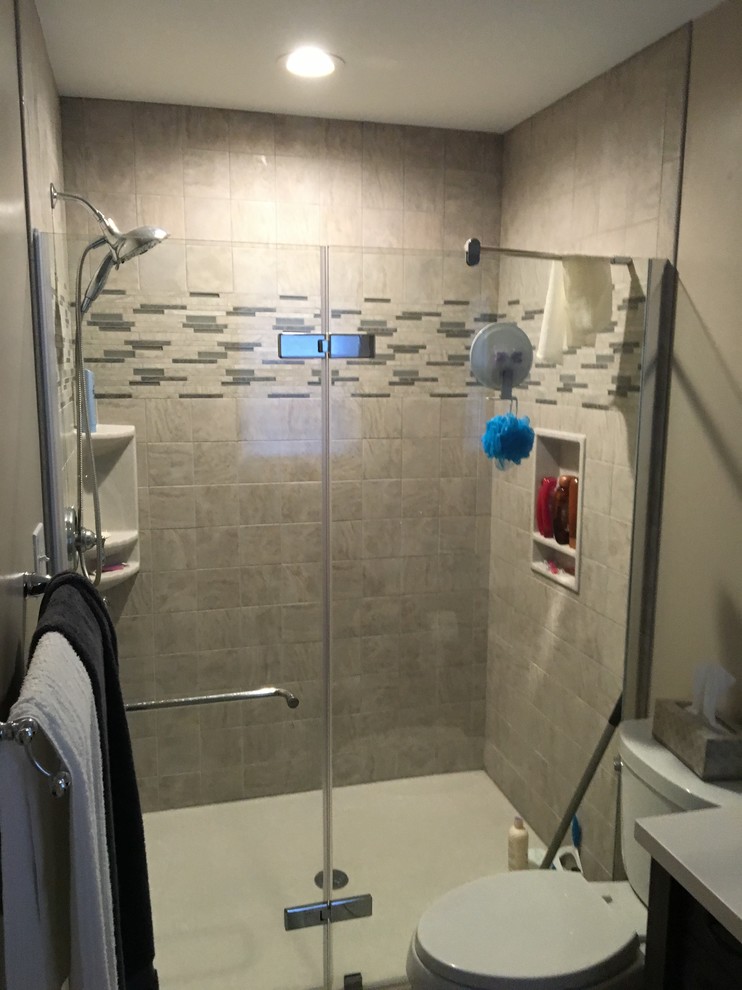 Example of a small transitional 3/4 alcove shower design in Baltimore with black cabinets, a one-piece toilet, brown walls, an undermount sink, solid surface countertops, a hinged shower door and white countertops