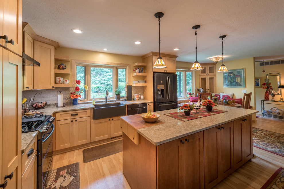 Photo of a large arts and crafts l-shaped eat-in kitchen in Minneapolis with a farmhouse sink, shaker cabinets, light wood cabinets, quartz benchtops, beige splashback, brick splashback, stainless steel appliances, light hardwood floors, with island, beige floor and beige benchtop.