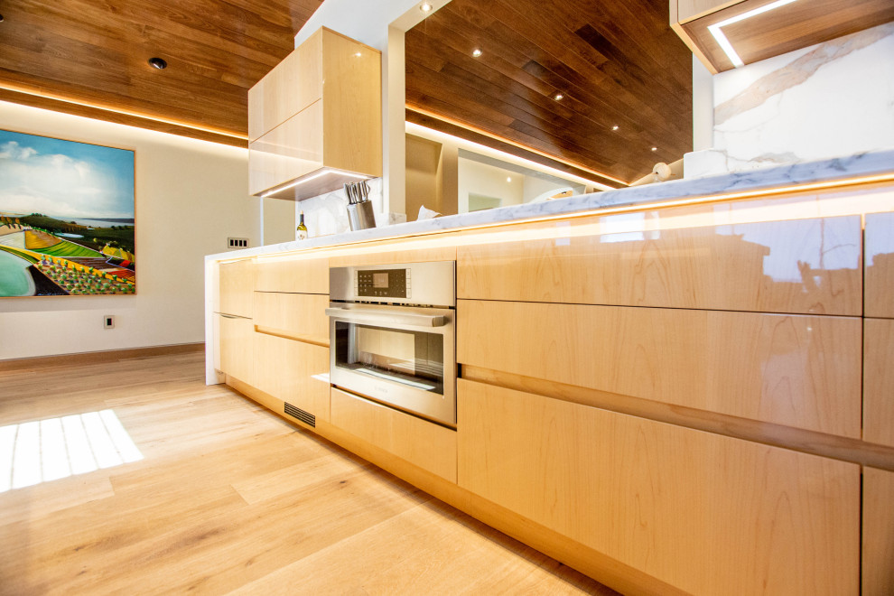 This is an example of a beach style l-shaped open plan kitchen in Other with an undermount sink, flat-panel cabinets, medium wood cabinets, stainless steel appliances, medium hardwood floors, with island, multi-coloured benchtop and wood.