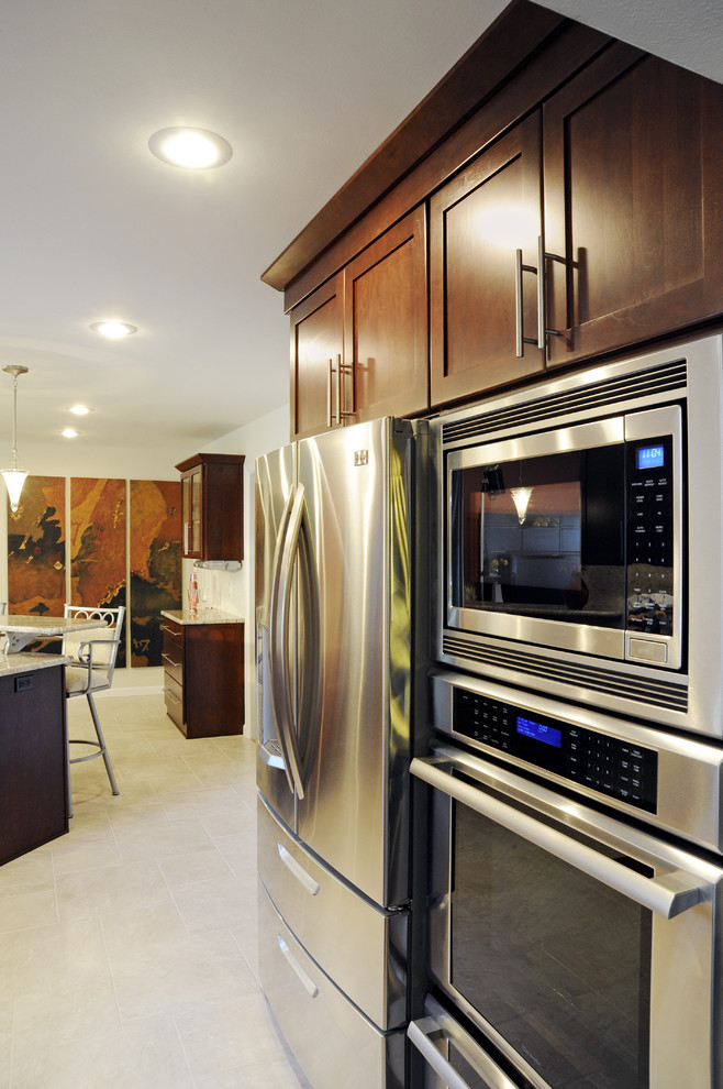Inspiration for a large transitional u-shaped ceramic tile and beige floor eat-in kitchen remodel with a double-bowl sink, shaker cabinets, dark wood cabinets, granite countertops, beige backsplash, mosaic tile backsplash, stainless steel appliances and a peninsula