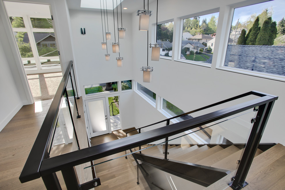 Example of a mid-sized minimalist light wood floor foyer design in Seattle with white walls and a glass front door