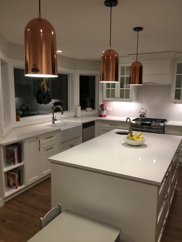 Example of a large transitional l-shaped eat-in kitchen design with a farmhouse sink, shaker cabinets, white cabinets, quartz countertops, stainless steel appliances, an island and white countertops