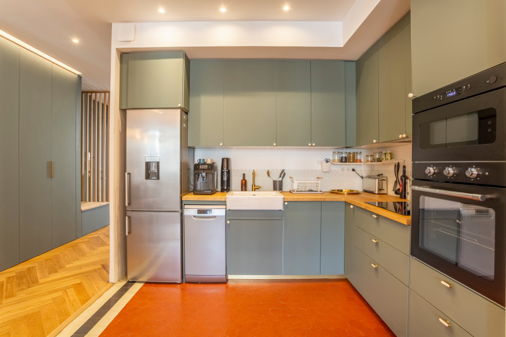 マルセイユにある高級な中くらいなトランジショナルスタイルのおしゃれなキッチン (エプロンフロントシンク、インセット扉のキャビネット、緑のキャビネット、木材カウンター、ベージュキッチンパネル、パネルと同色の調理設備、テラコッタタイルの床、アイランドなし、赤い床、ベージュのキッチンカウンター) の写真