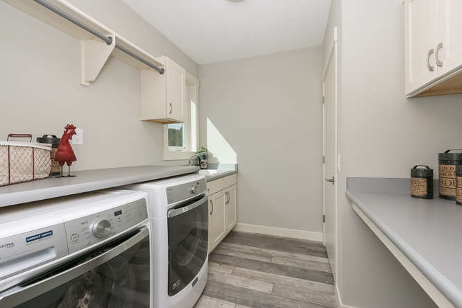 Inspiration for a mid-sized contemporary galley dedicated laundry room in Minneapolis with an utility sink, recessed-panel cabinets, white cabinets, grey walls and a side-by-side washer and dryer.