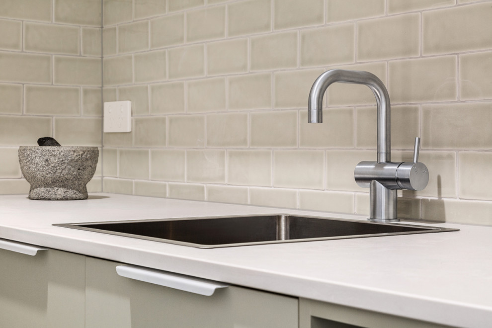 Inspiration for a small contemporary kitchen pantry in Melbourne with a drop-in sink, green cabinets, quartz benchtops, green splashback, subway tile splashback, stainless steel appliances, ceramic floors and grey benchtop.